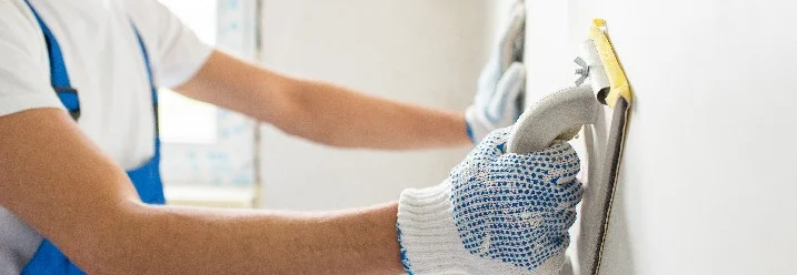 Person schleift Wand mit Schleifklotz